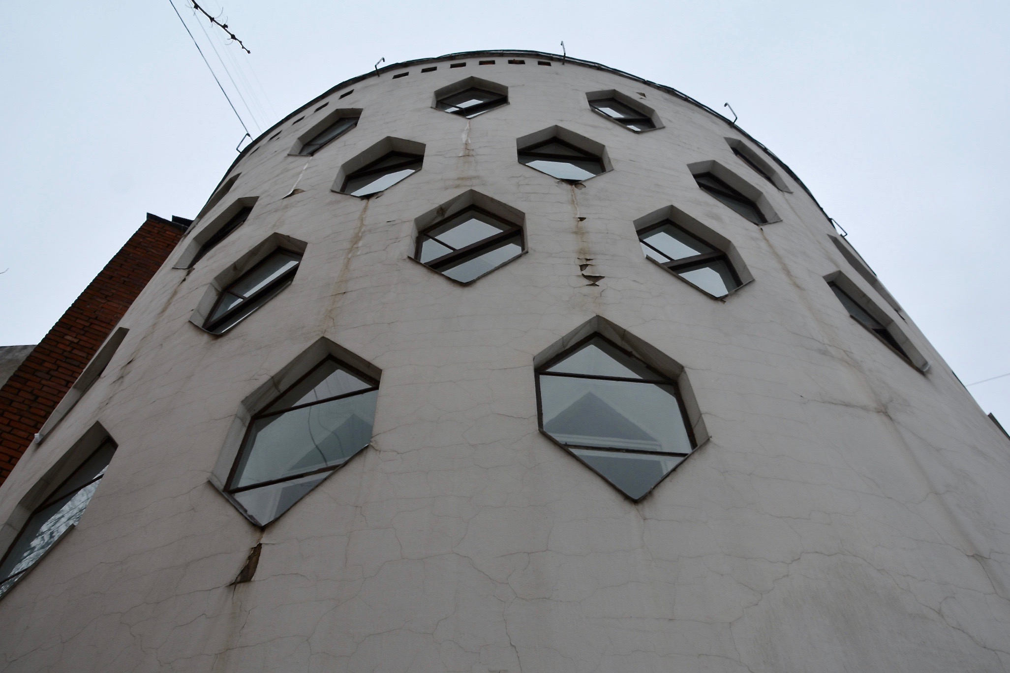 looking up at the facade of the Melnikov House in Moscow featuring the honeycomb shaped windows on a grey day