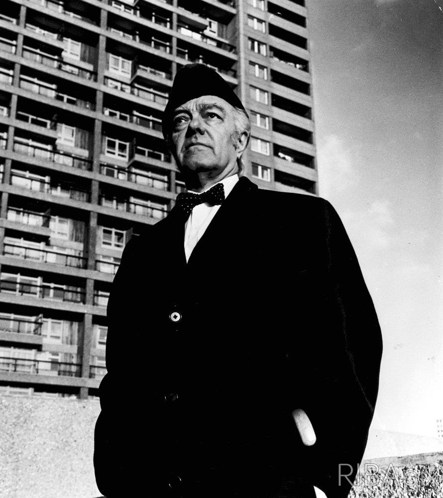goldfinger with astrakan hat on in front of brutalist Trellick