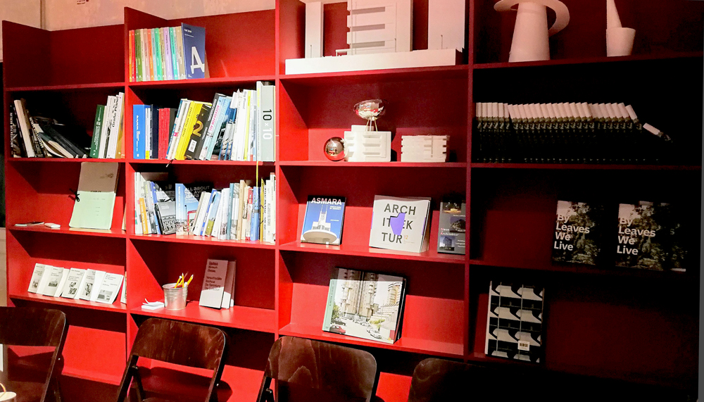 red bookcase with architecture books and chairs in cafe of leibling haus tel aviv