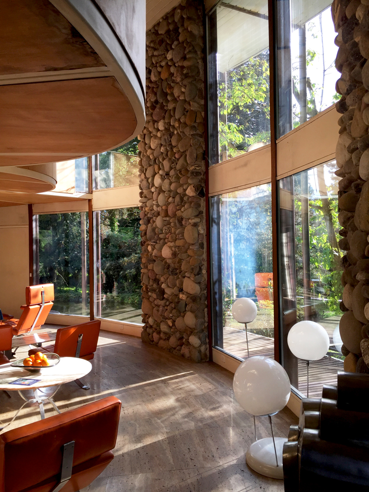 inside villa kolb with stone wall detail and orange chairs 