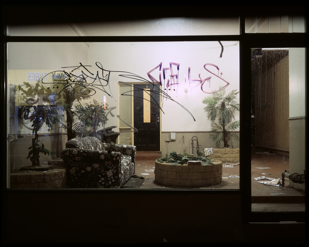 downtown hotel lobby in poor condition with letters thrown on the floor and graffiti on window 