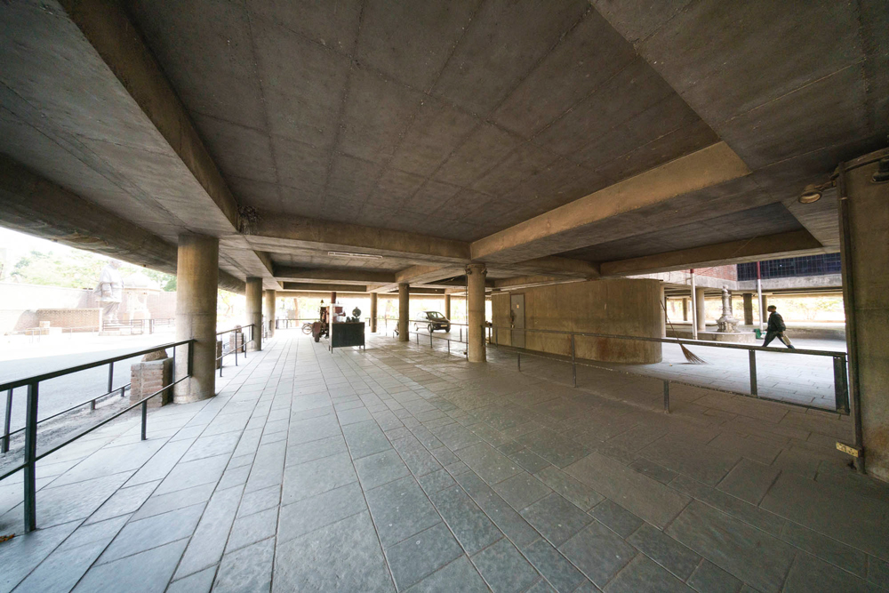 ground level with people walking under the corbusier city museum Ahmedabad