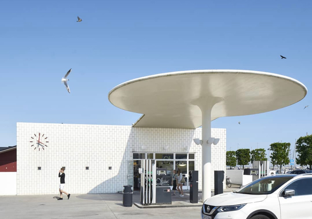 forecourt of white arne jacobsen petrol station with white car parked outside