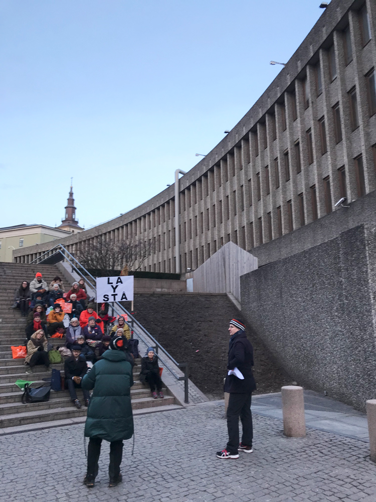 protestors sitting on steps with banners