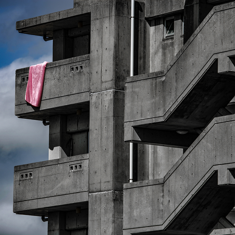 brutalist apartment block with flash of pink on balcony