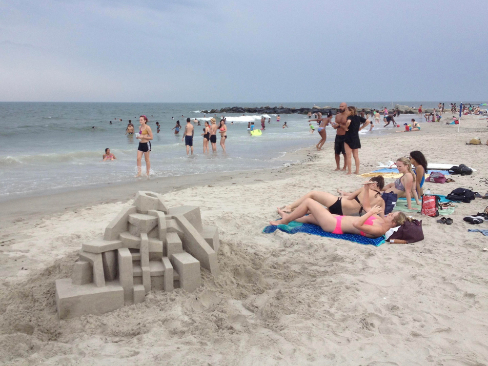 sunbathers lying next to one of calvin seibert's sandcastles