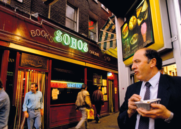 man looking at soho book shop whilst eating take out