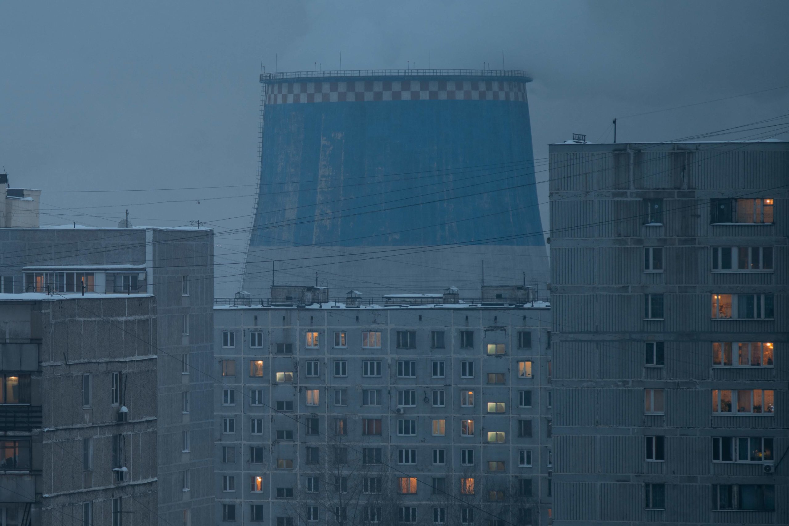 cooling tower of power plant looming over residential buildings