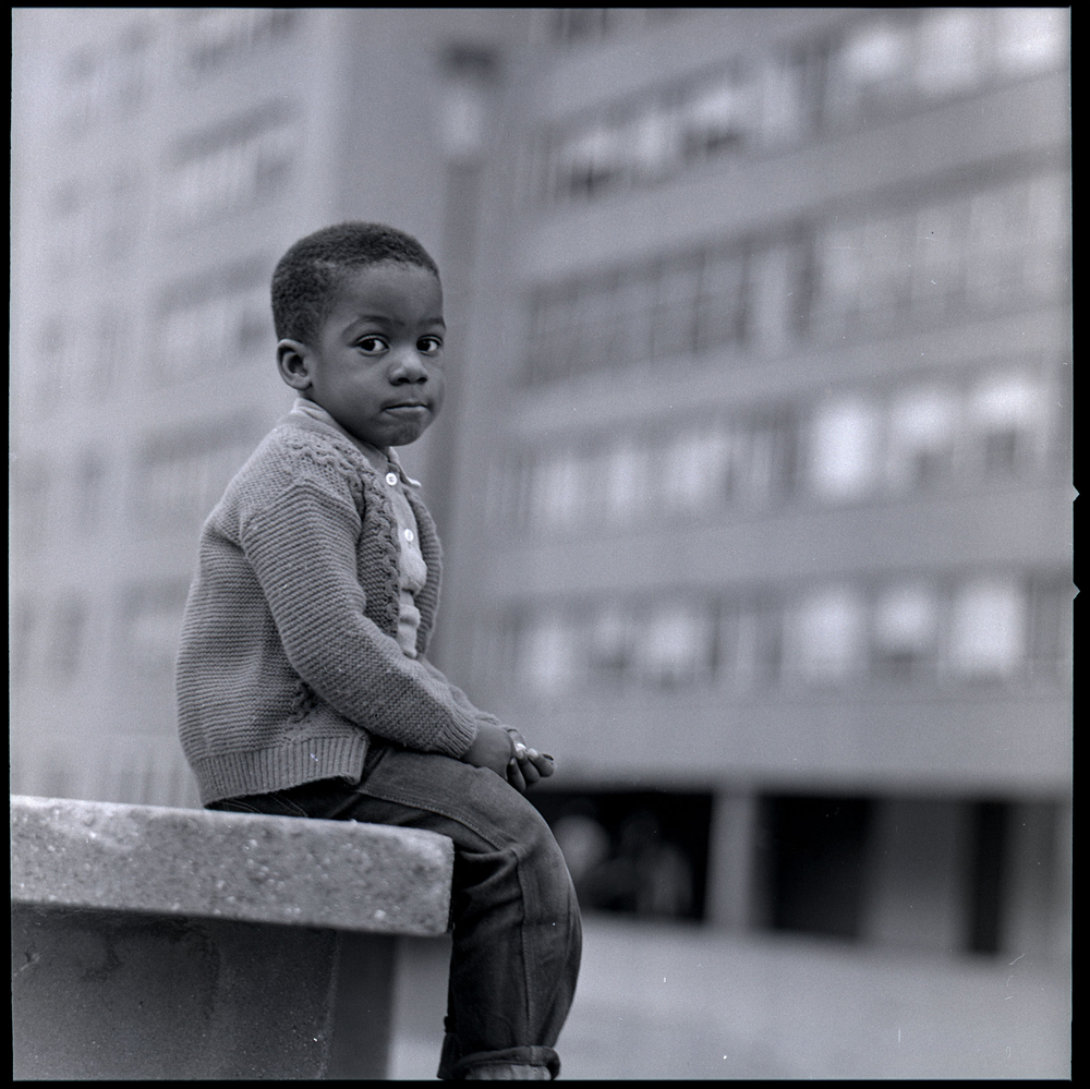 Child sitting in front of a Pruitt-Igoe block