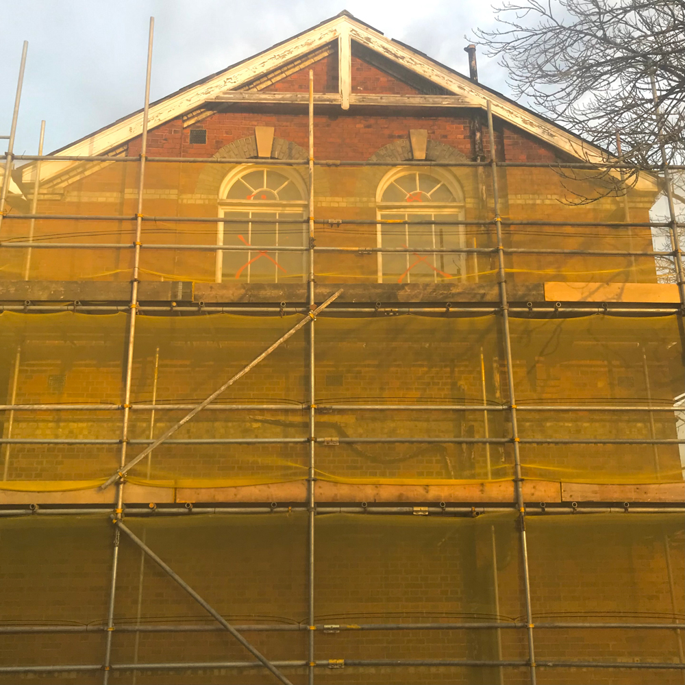 house in Muswell Hill covered in protective netting shot in a gold light