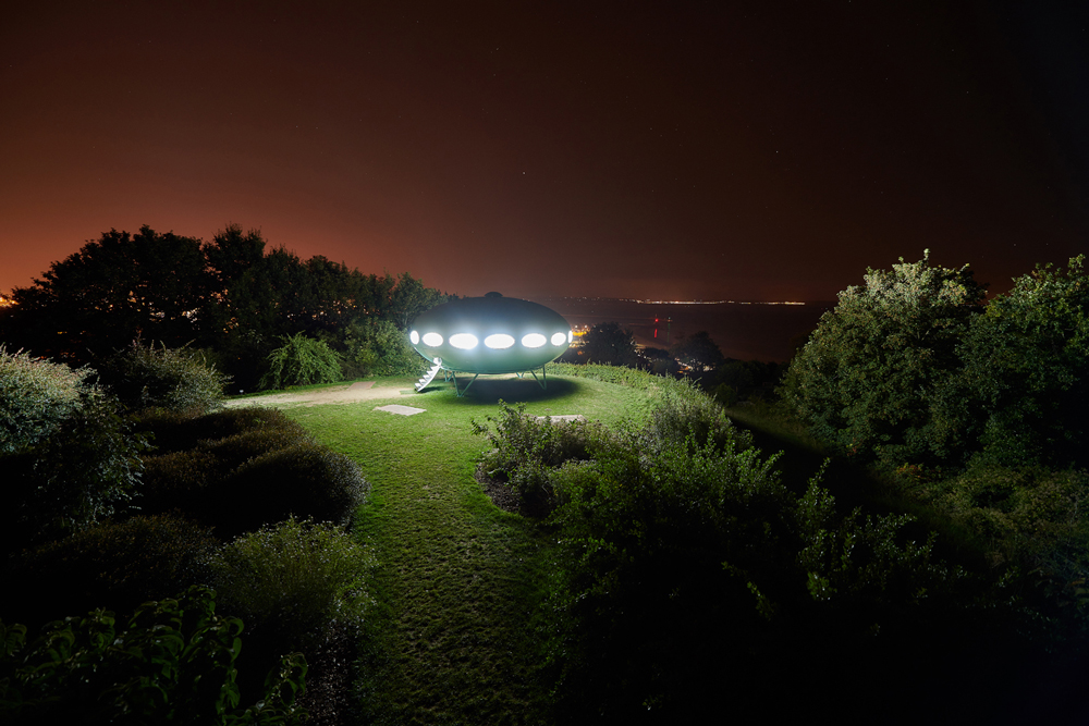 futuro house lit at night on a hillside 